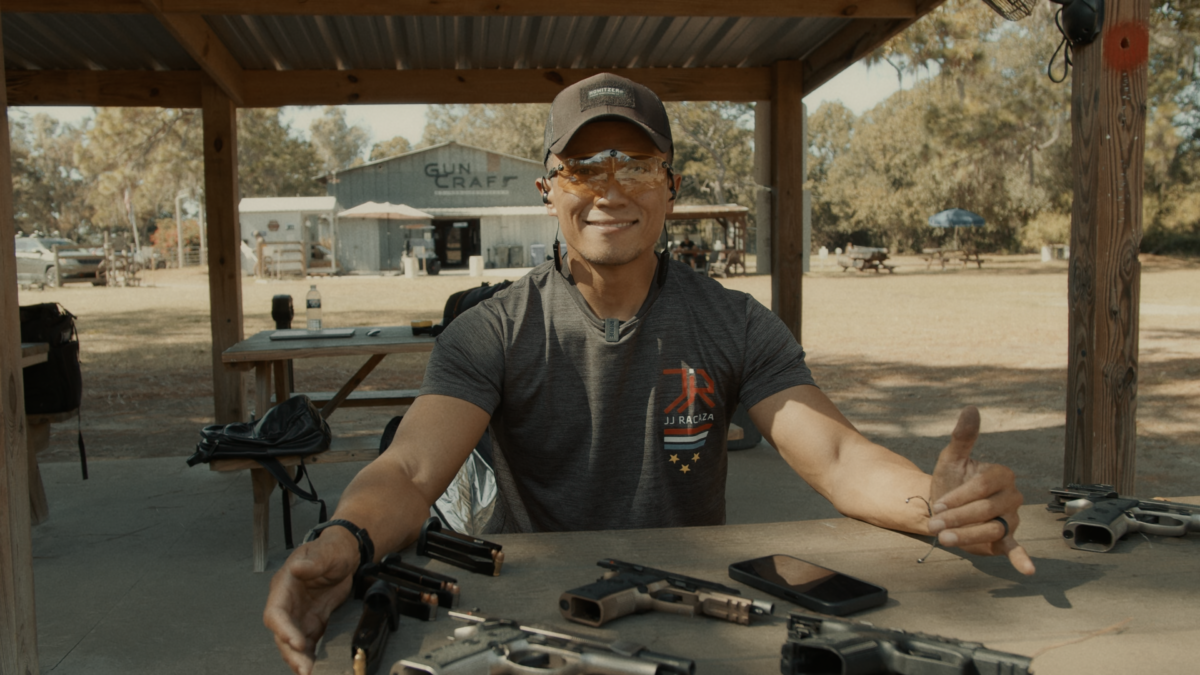 JJ Racaza sitting at the table, on table there are EDC and competition guns